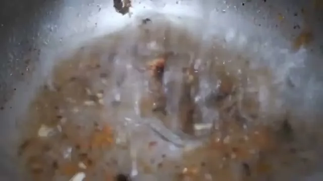 Murky camera view of brown debris and film coating the inside of a pipe