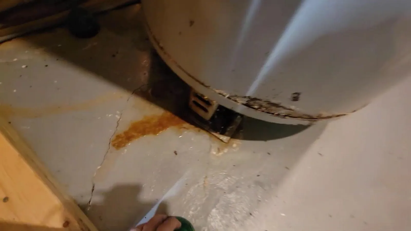 Orange rust stains and a crack in the concrete floor under the base of a water heater