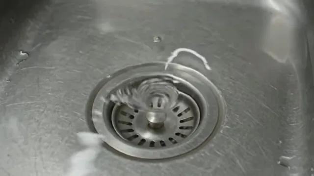Stainless sink basin with water draining slowly around a perforated strainer